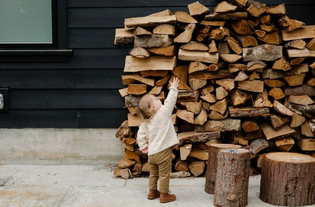 child outside by massive pile of chopped wood