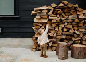 child outside by massive pile of chopped wood