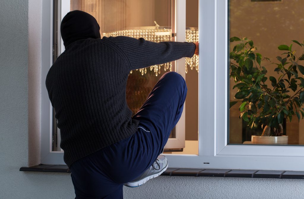 burglar climbing through window from the outside